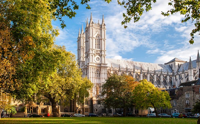 Westminster Abbey in London surrounded by trees on a sunny day.