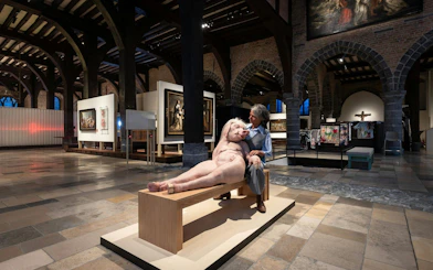 Exhibit inside Museum Sint-Janshospitaal featuring a unique sculpture and historical paintings.