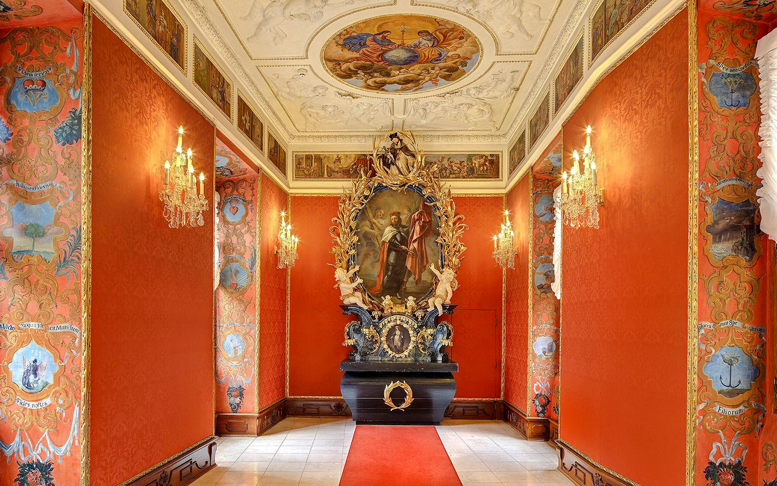 Ornate hallway with red walls and chandeliers inside Lobkowicz Palace Museum, Prague Castle.