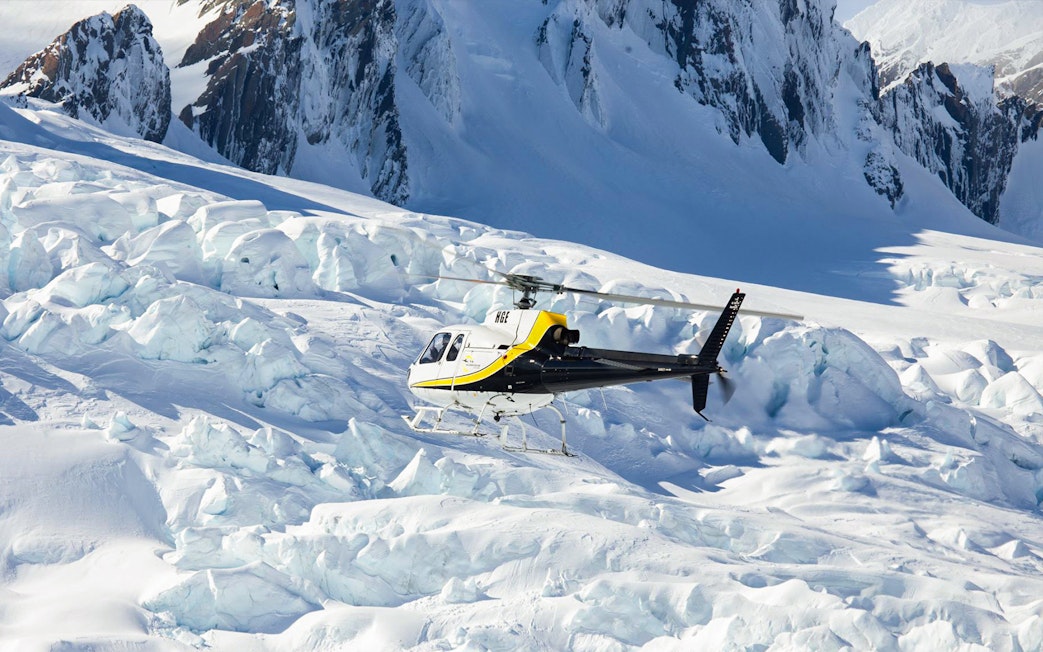 Helicopter approaching Franz Josef Glacier on scenic flight tour.