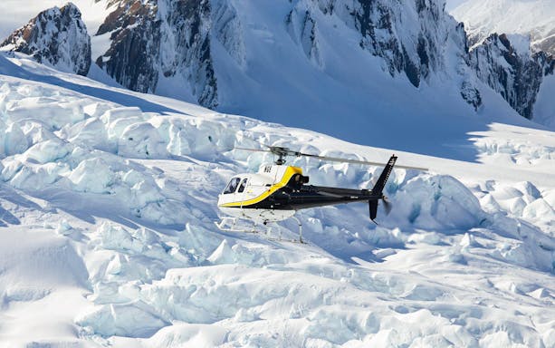 Helicopter approaching Franz Josef Glacier on scenic flight tour.