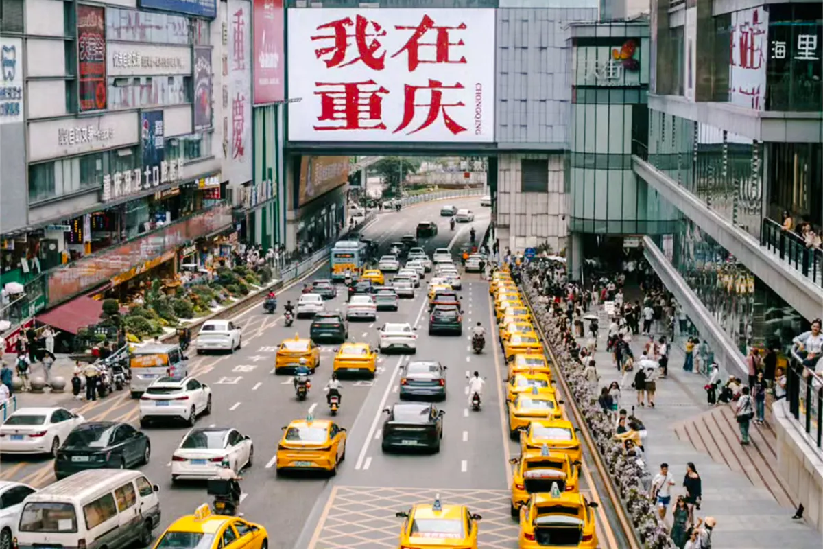 Chongqing city street with yellow taxis and pedestrians, showcasing urban life.