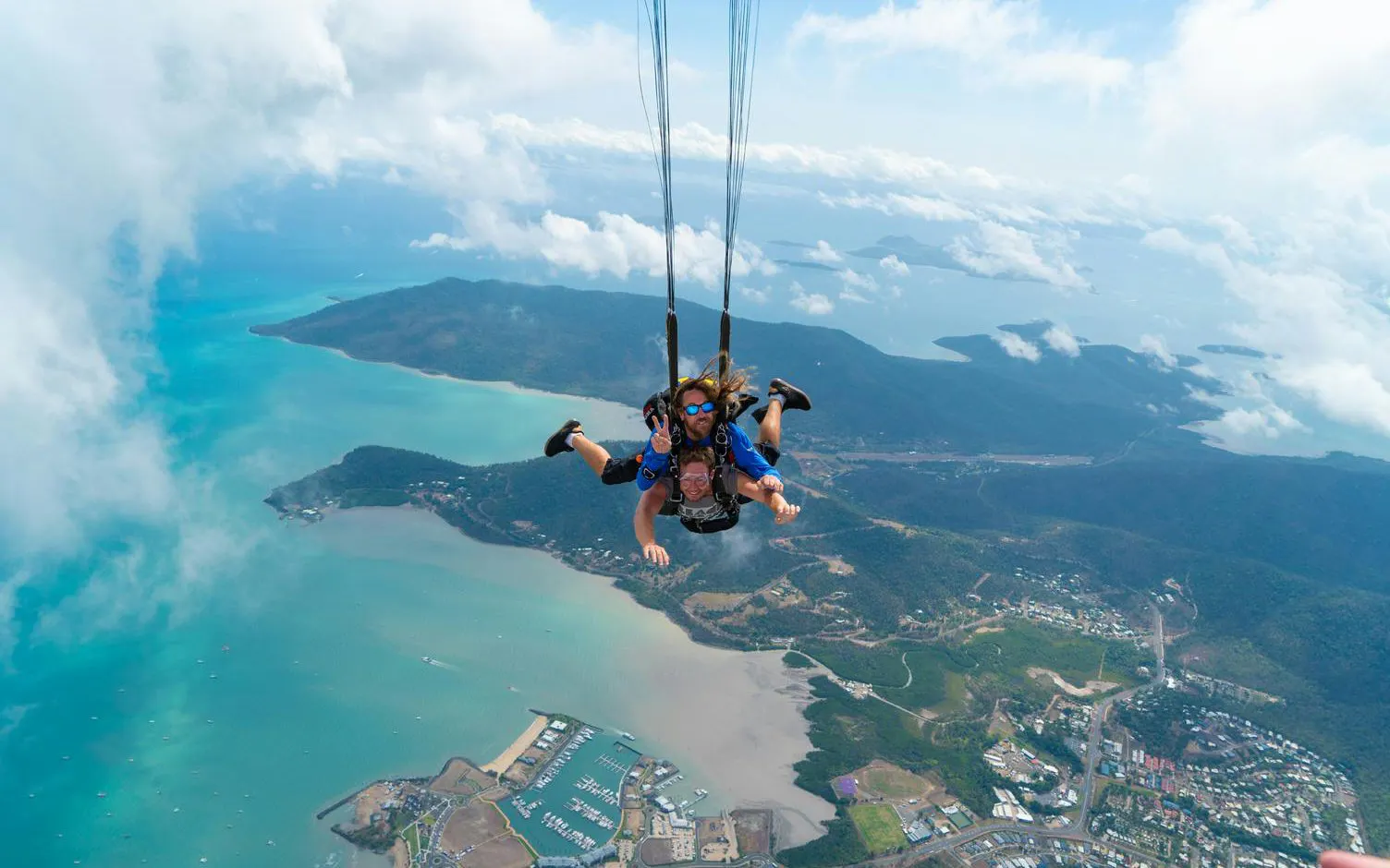Tandem skydive over Airlie Beach with ocean and islands below.