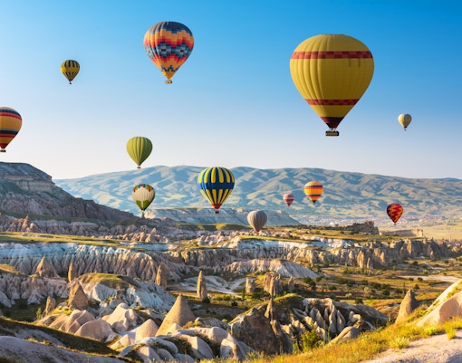 Cappadocia hot air balloons floating over unique rock formations in Turkey.