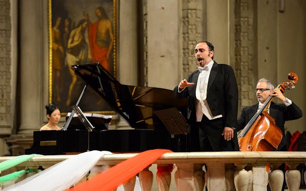 Tenor performing with pianist and cellist at a concert in Florence.