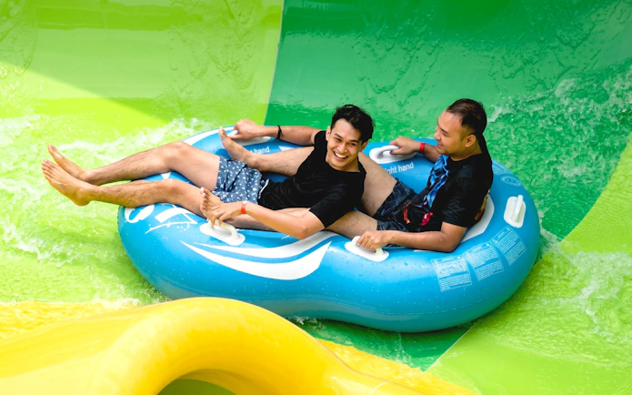 People riding a blue inflatable raft at SplashMania Waterpark.