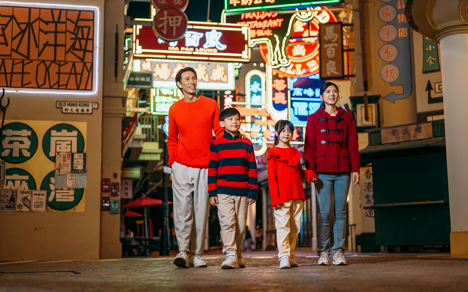 Family walking through neon-lit street at Ocean Park Hong Kong.