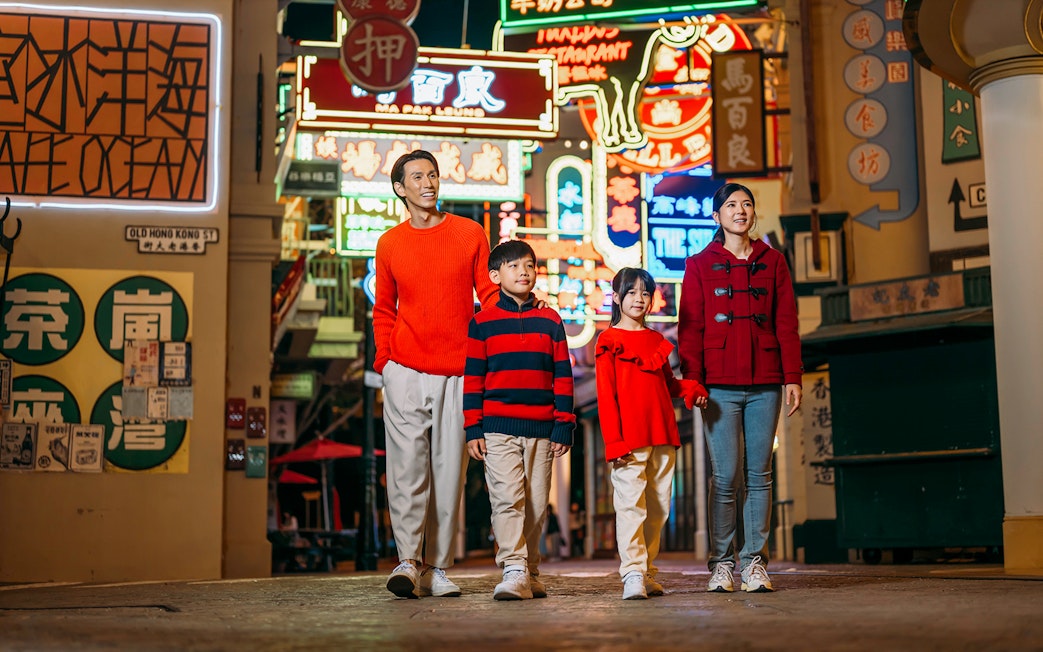 Family walking through neon-lit street at Ocean Park Hong Kong.