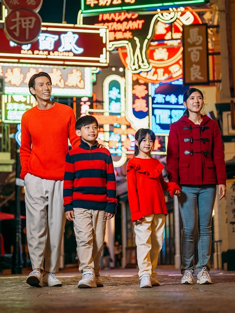 Family walking through neon-lit street at Ocean Park Hong Kong.