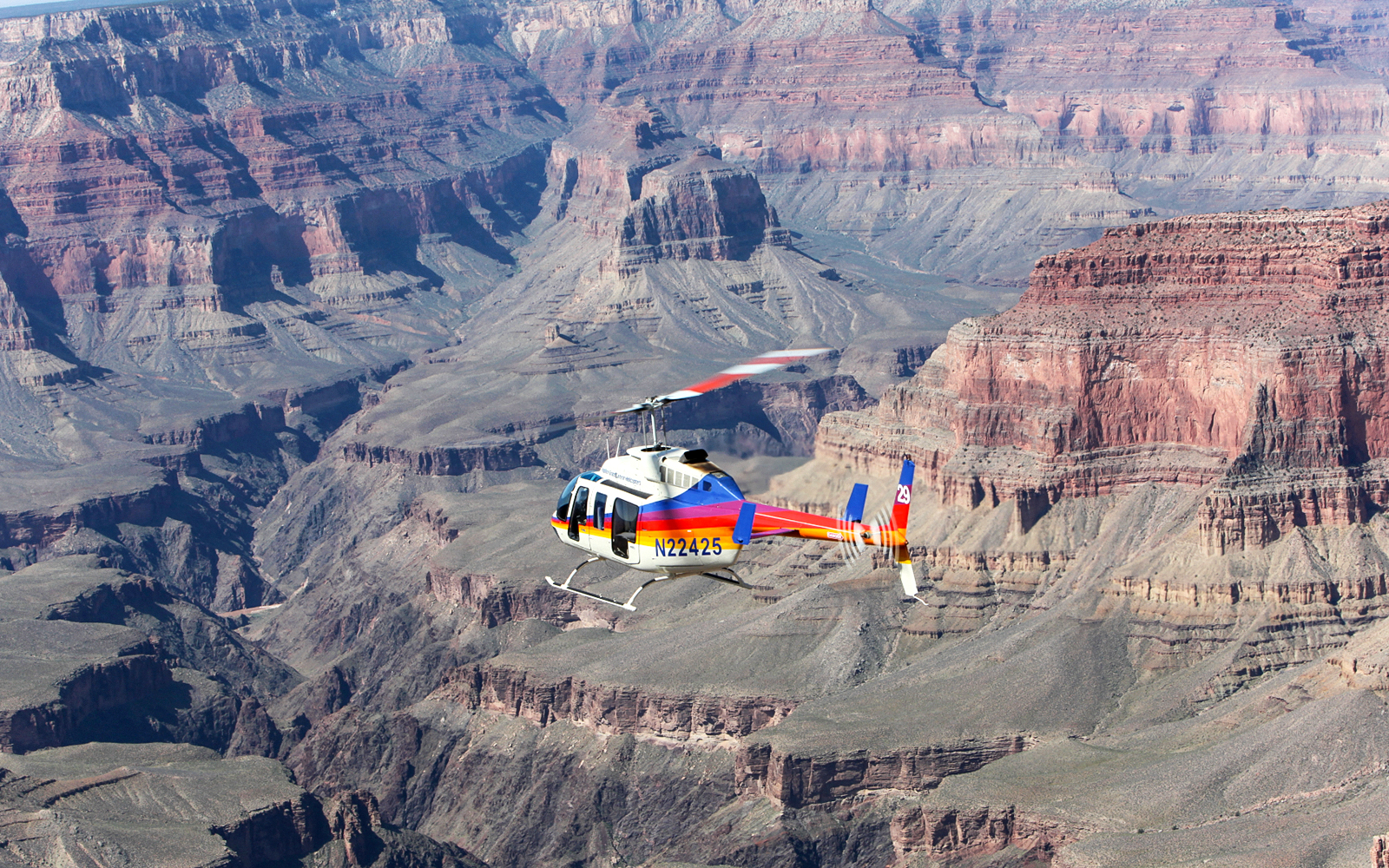 Helicopter flying over the Grand Canyon's vast rock formations.