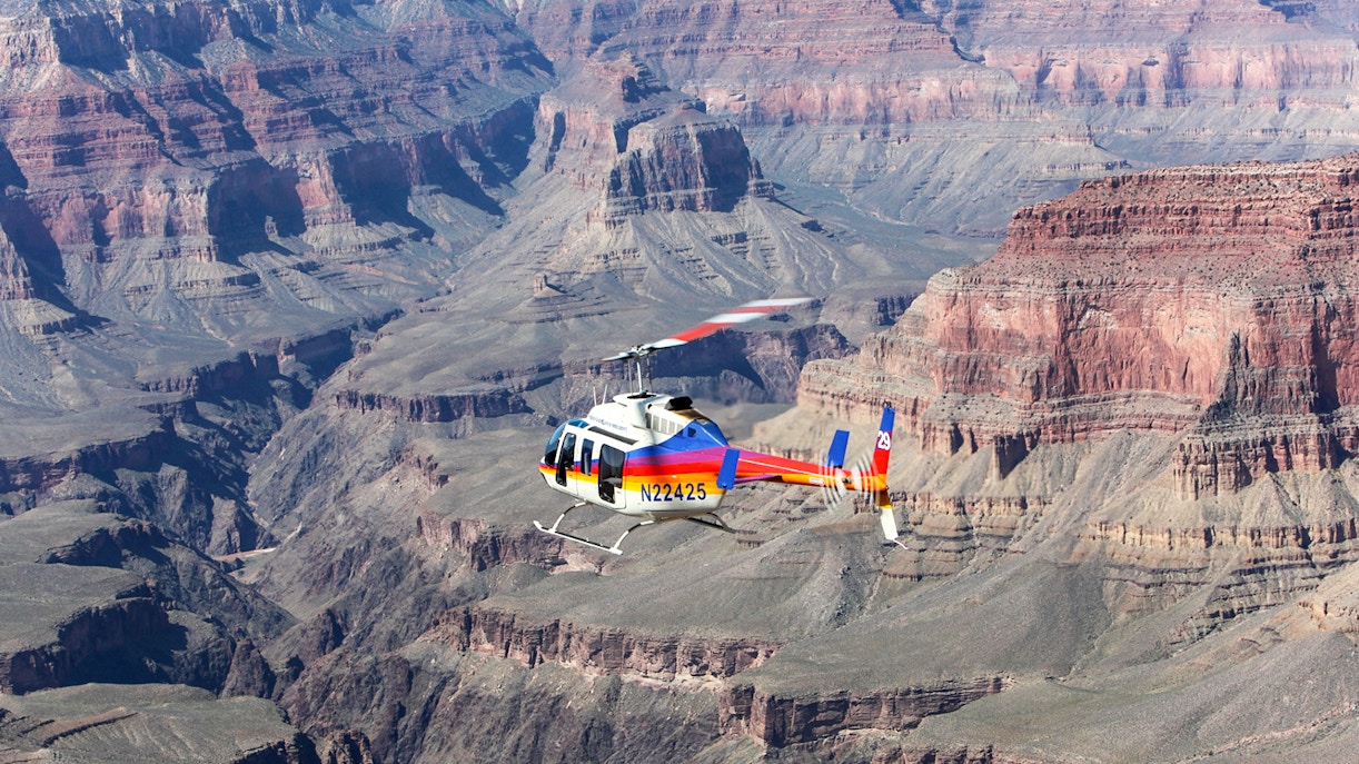 Helicopter flying over the Grand Canyon South Rim, showcasing vast canyon views.