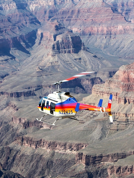 Helicopter flying over the Grand Canyon's vast rock formations.