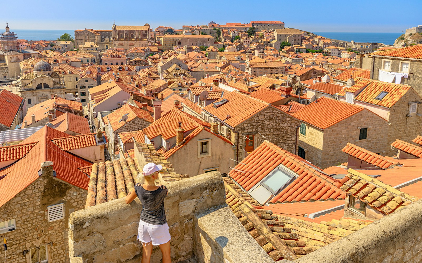 Aerial view of Dubrovnik's red rooftops with a girl on the city walls, Croatia.