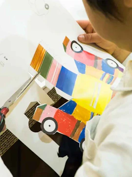Child cutting colorful paper car at teamLab Future Park.