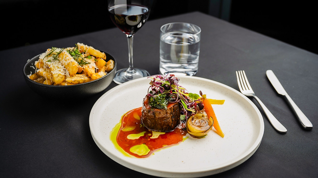 Steak dinner with vegetables and wine at Melbourne Skydeck dining experience.