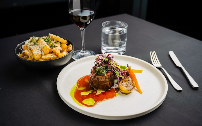 Steak dinner with vegetables and wine at Melbourne Skydeck dining experience.