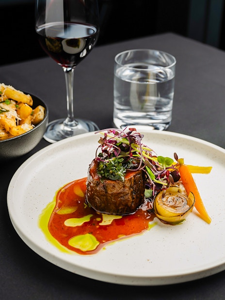 Steak dinner with vegetables and wine at Melbourne Skydeck dining experience.