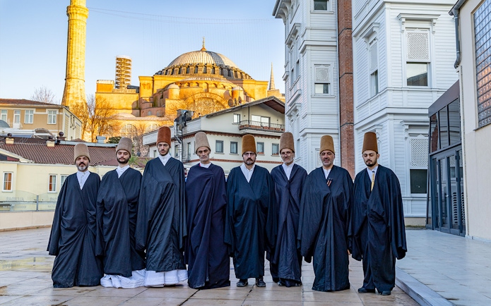 Whirling dervishes in traditional attire standing in front of Hagia Sophia, Istanbul.