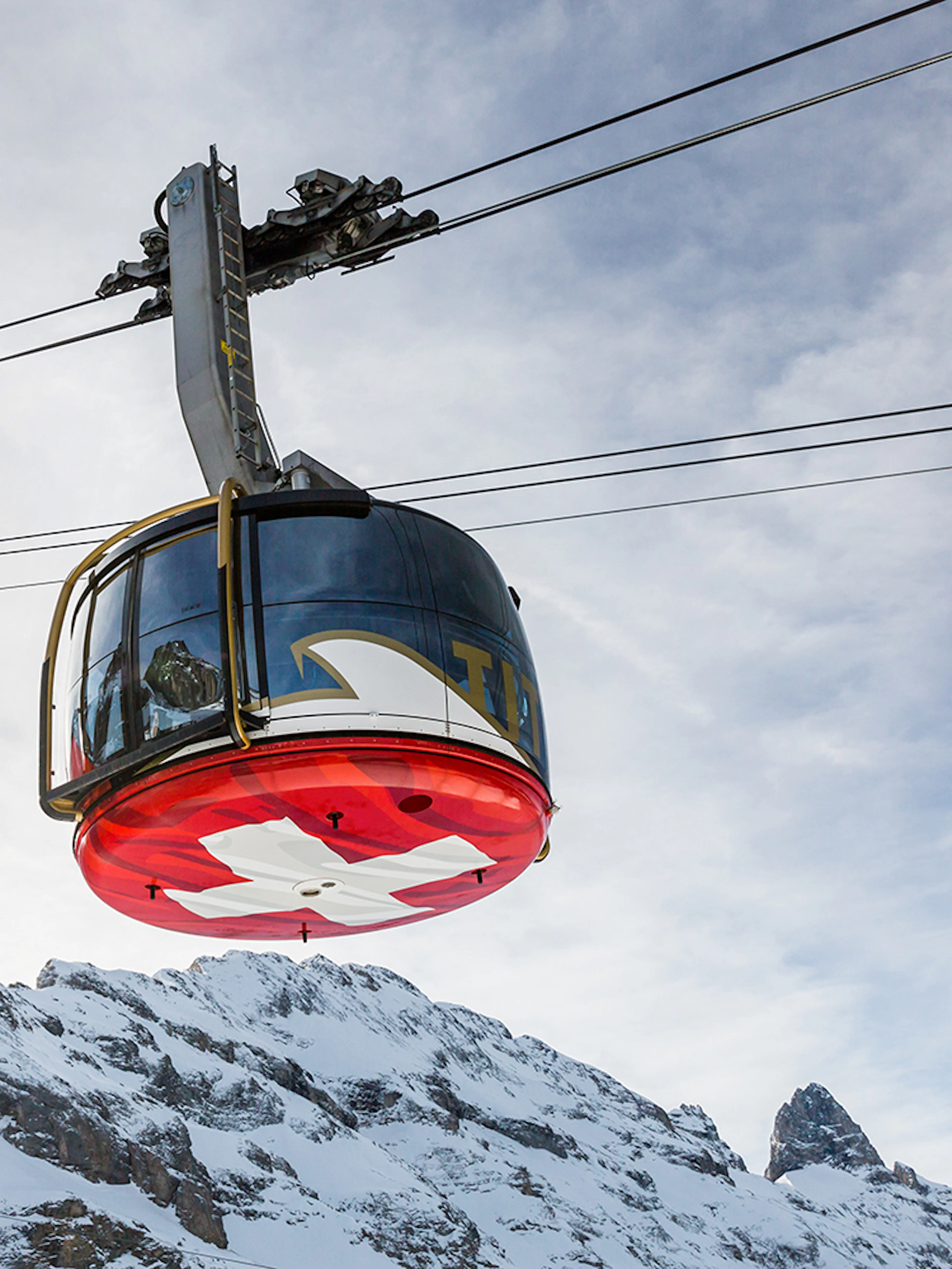Titlis Cableways gondola ascending from Engelberg with snowy mountain backdrop.