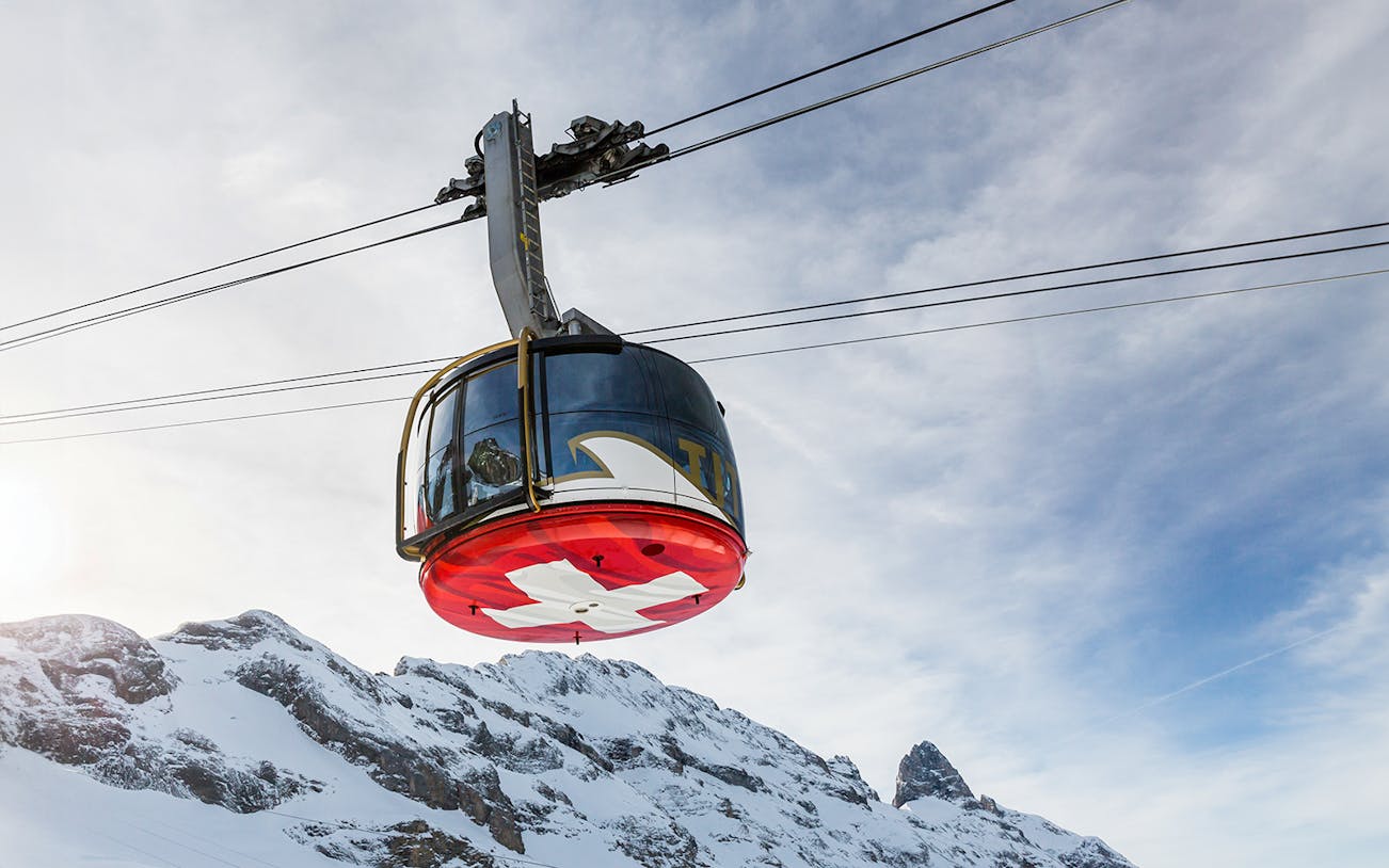 Titlis Cableways gondola ascending from Engelberg with snowy mountain backdrop.