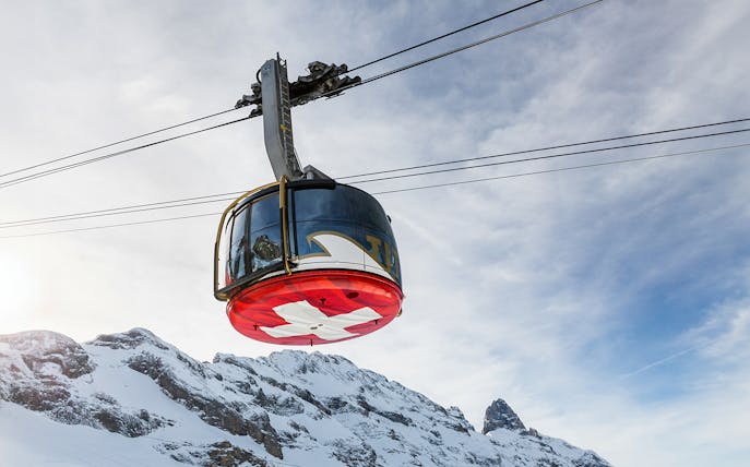 Titlis Cableways gondola ascending from Engelberg with snowy mountain backdrop.