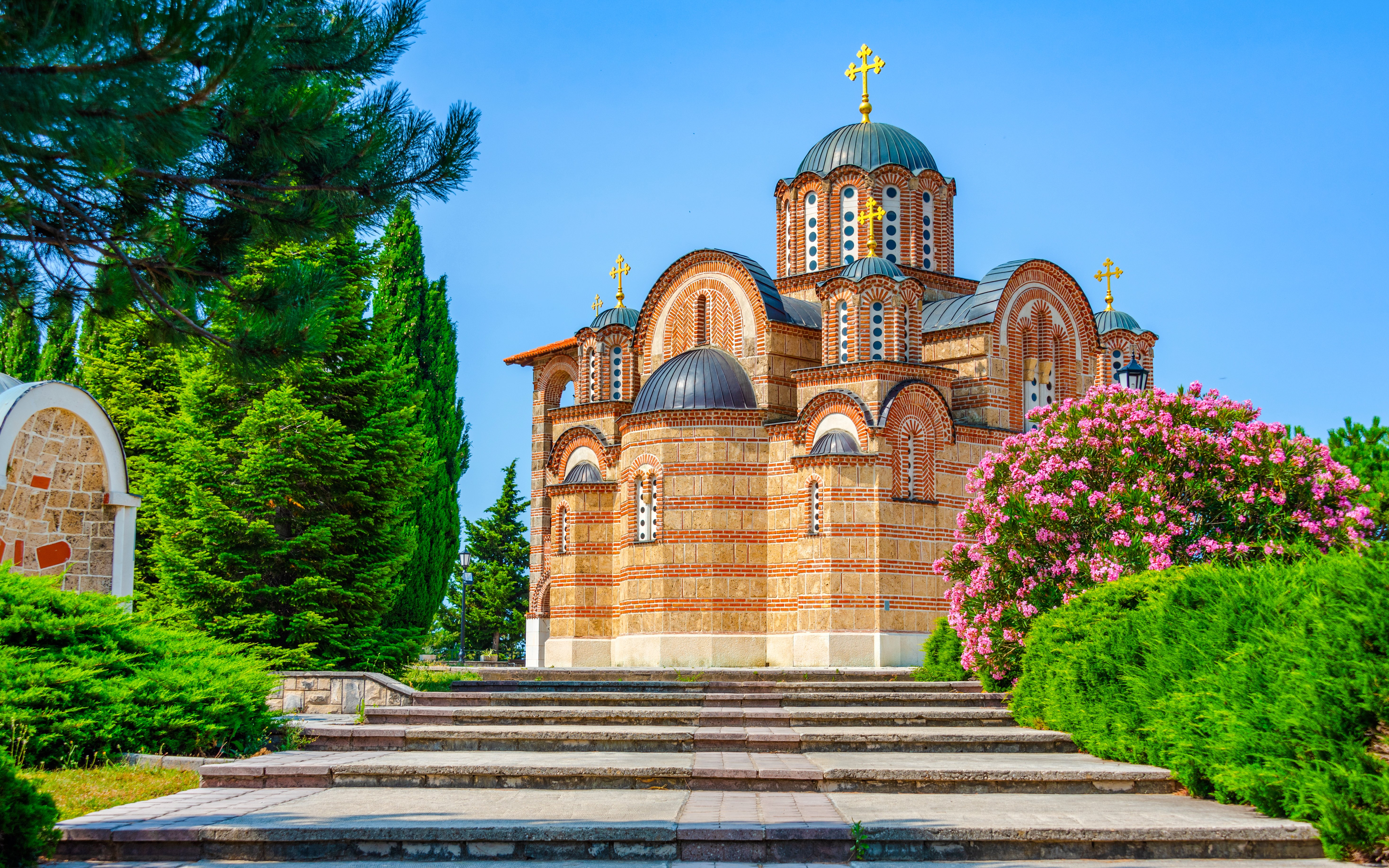 Hercegovacka Gracanica Temple with domes and arches in Trebinje, Bosnia, surrounded by greenery.