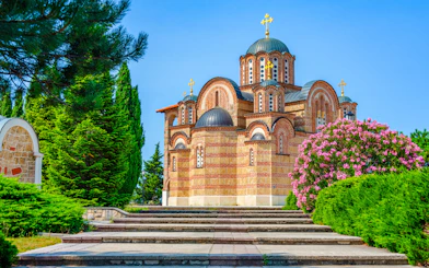 Hercegovacka Gracanica Temple with domes and arches in Trebinje, Bosnia, surrounded by greenery.