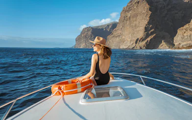 Woman on yacht with lifebuoy sailing near rocky coast of Tenerife.