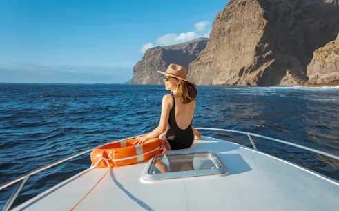 Woman on yacht with lifebuoy sailing near rocky coast of Tenerife.