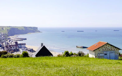 Coastal view of Arromanches-les-Bains, Normandy, with beach and sea in the background.