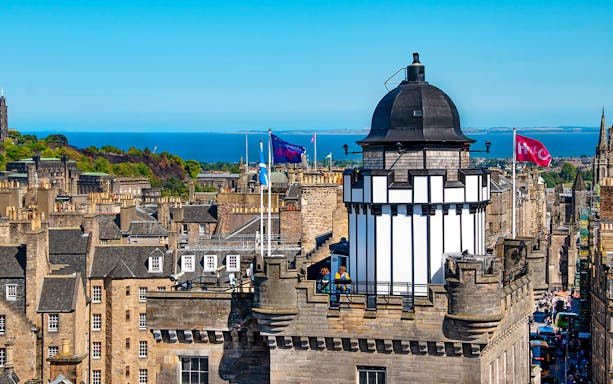 Camera Obscura & World of Illusions tower with Edinburgh skyline and sea in the background.