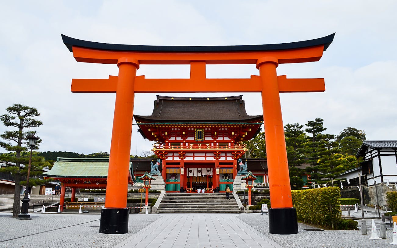 Fushimi Inari Taisha shrine entrance with iconic red torii gate, Kyoto, Japan.