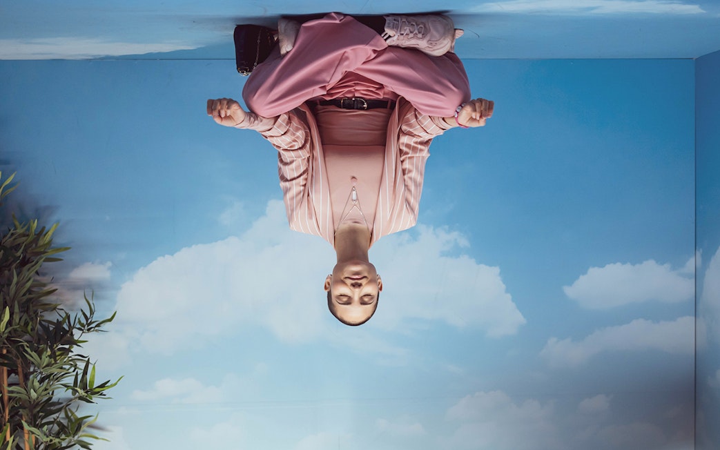 Person meditating in a room with sky and clouds at Pink Palace.