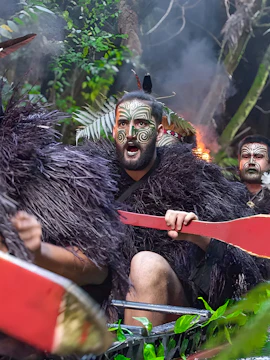 Warriors paddling a canoe at Mitai Maori Village, New Zealand.
