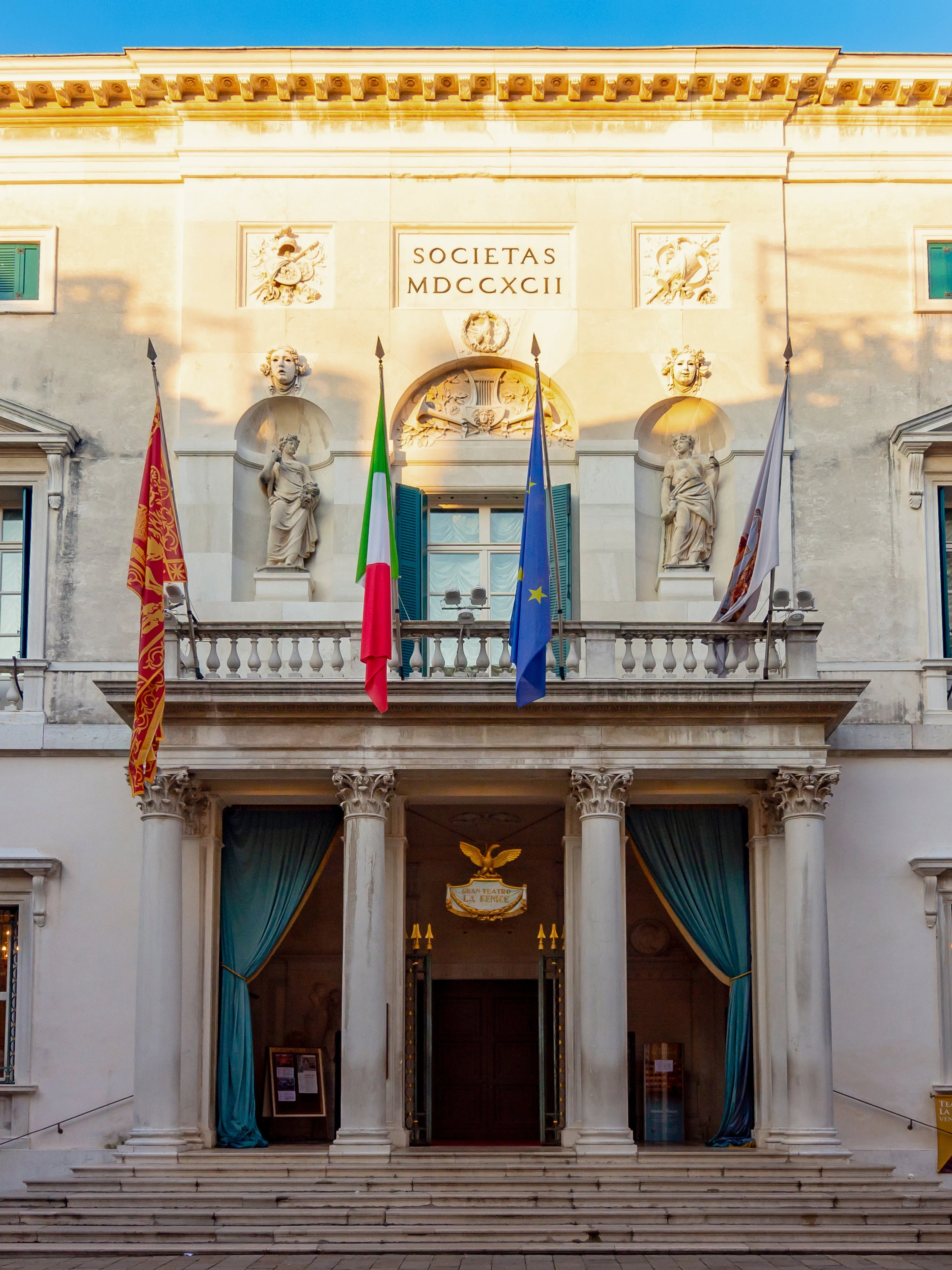 Teatro La Fenice facade with flags and statues, Venice, Italy.
