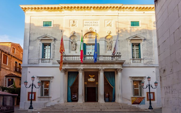 Teatro La Fenice facade with flags and statues, Venice, Italy.