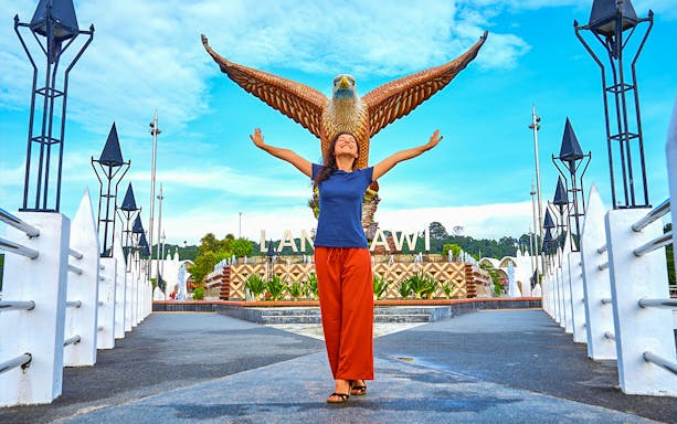 Langkawi Eagle Square with a person standing in front, arms raised.