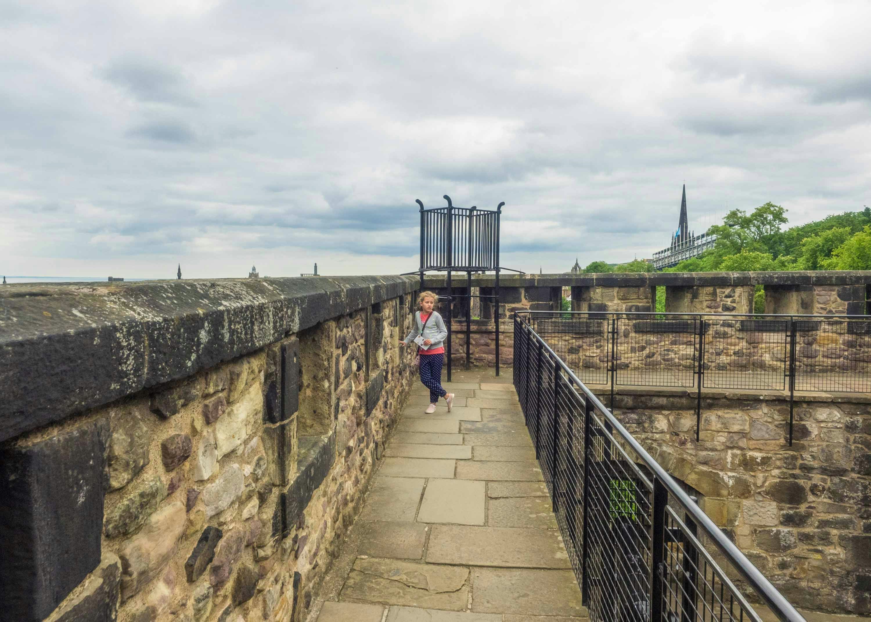 Edinburgh Castle ramparts with view of historic architecture and visitor exploring.