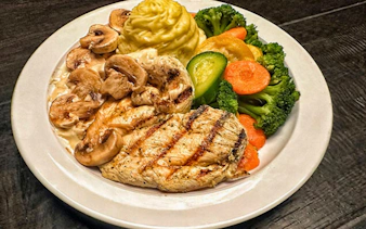 Grilled chicken with mushrooms, mashed potatoes, and mixed vegetables served at Orlando's 1920s speakeasy dinner show.