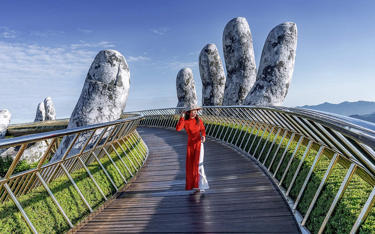 Golden Bridge in Ba Na Hills with a person walking, surrounded by giant stone hands.