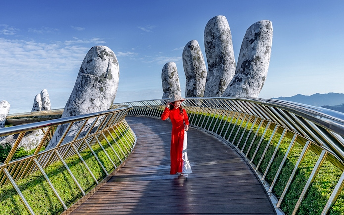 Golden Bridge in Ba Na Hills with a person walking, surrounded by giant stone hands.