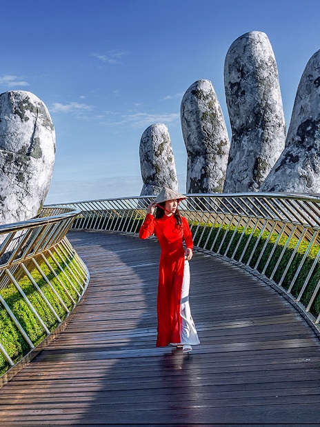 Golden Bridge in Ba Na Hills with a person walking, surrounded by giant stone hands.