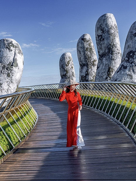 Golden Bridge in Ba Na Hills with a person walking, surrounded by giant stone hands.
