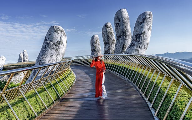 Golden Bridge in Ba Na Hills with a person walking, surrounded by giant stone hands.