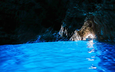 Boat entering Blue Grotto cave with vibrant blue water on Capri, Italy.
