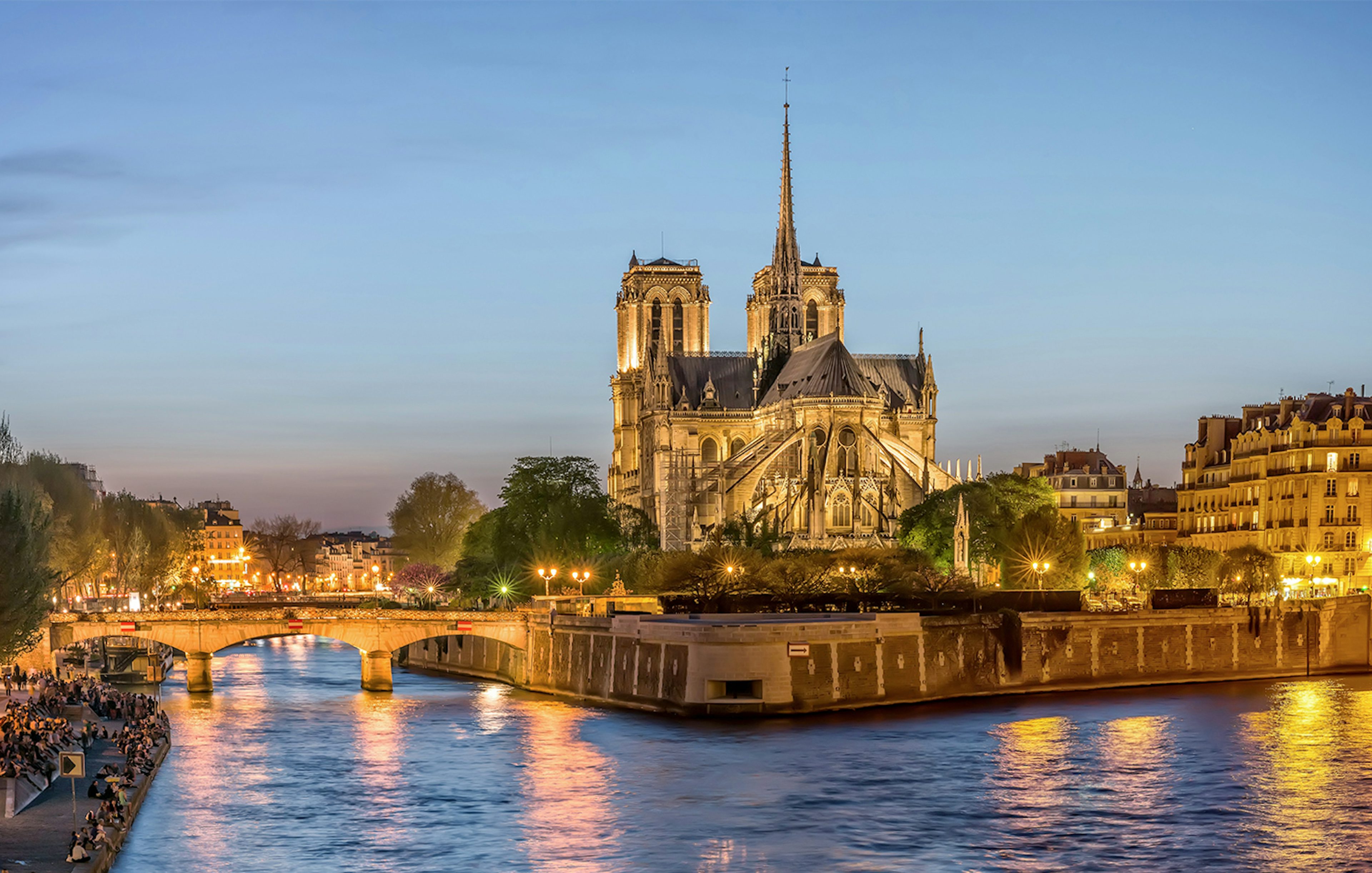 Notre-Dame de Paris illuminated at dusk during city tour along the Seine River.