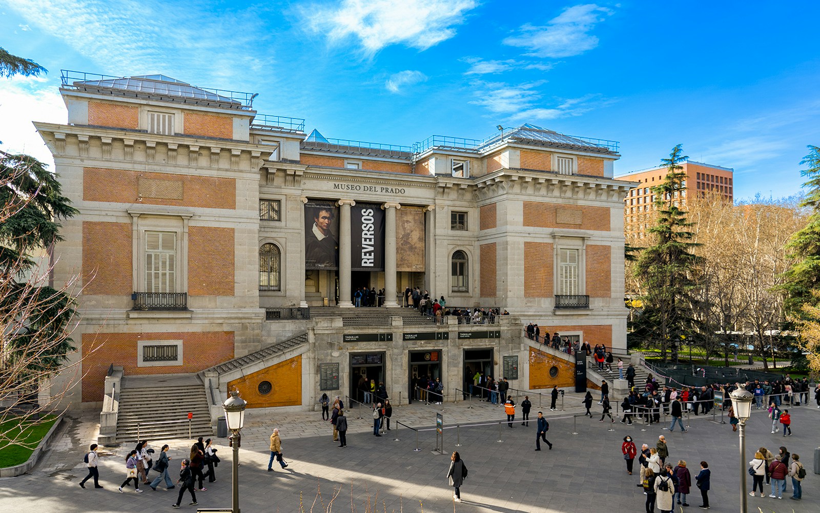 Visitors exploring art exhibits inside Prado Museum, Madrid, during a guided tour.