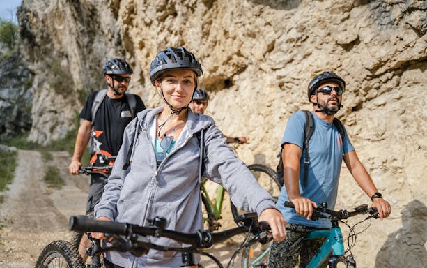 Group riding electric bikes on rocky trail.