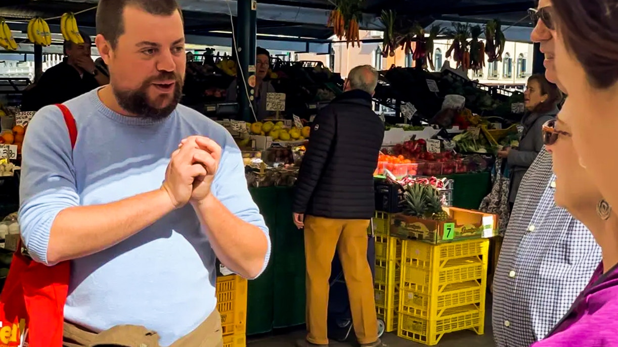 Tour guide explaining at Rialto Market during Venice street food tour.