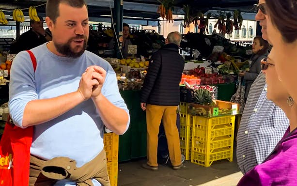 Tour guide explaining at Rialto Market during Venice street food tour.